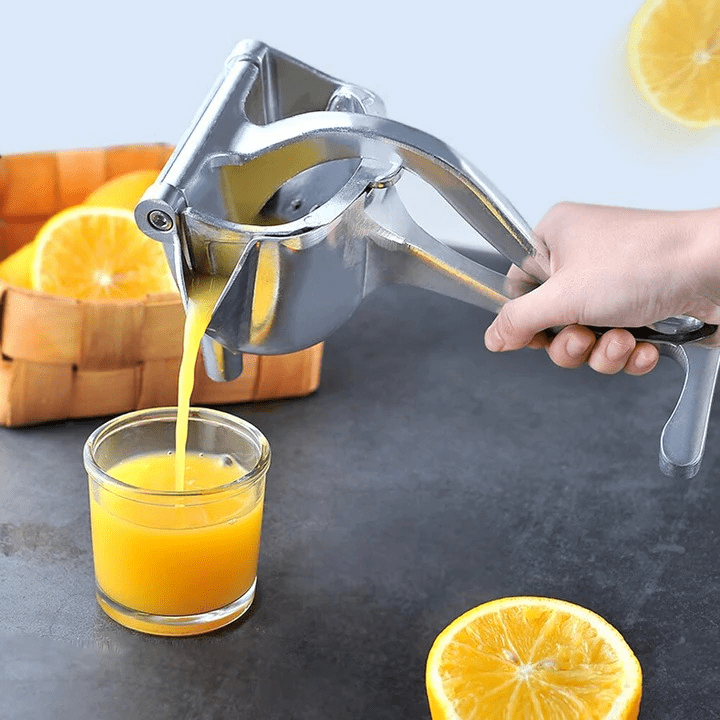Exprimidor de frutas metálico exprimiendo jugo de naranja en vaso